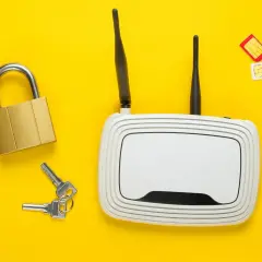 Zapewnij bezpieczeństwo swojego **internetu domowego**! Na żółtym tle leżą: biały router Wi-Fi, złota kłódka z kluczami oraz trzy karty SIM.