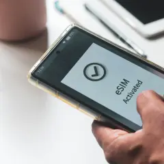 Dłoń trzyma smartfon z aktywowanym eSIM. Dowiedz się, jak przenieść eSIM na inny telefon, by cieszyć się mobilnością.