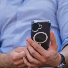 Mężczyzna w niebieskiej koszuli trzyma telefon z widocznym okręgiem, który sugeruje zaawansowaną haptykę.