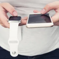 Ręce trzymające Apple Watch i iPhone. Dowiedz się, jak włączyć Apple Watch, parując go z telefonem.