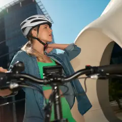 Kobieta w kasku i sportowym stroju na rowerze miejskim, gotowa do jazdy. Aplikacja na rower pomoże zaplanować trasę.