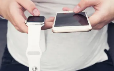 Ręce trzymające Apple Watch i iPhone. Dowiedz się, jak włączyć Apple Watch, parując go z telefonem.