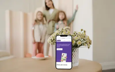 Telefon z aplikacją Bezpieczna Rodzina Play. Mama z córkami w tle.