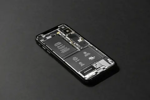 Rozłożony iPhone z widoczną baterią. Zastanawiasz się, ile trwa wymiana baterii w iPhone? To zależy od serwisu.