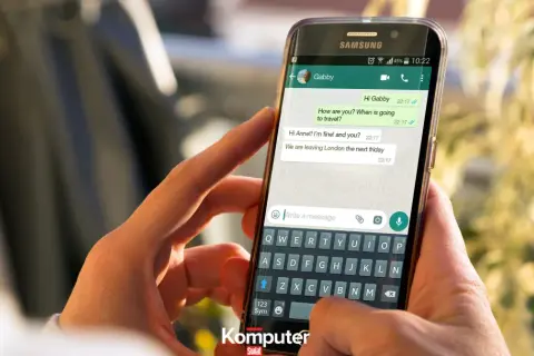 Dłoń trzyma smartfon z otwartym WhatsAppem, pokazując rozmowę. Dowiedz się, jak zainstalować WhatsApp.