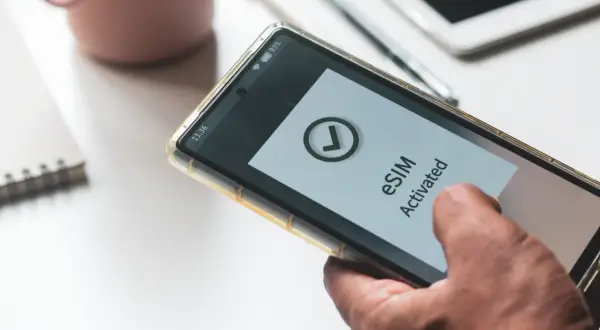 Dłoń trzyma smartfon z aktywowanym eSIM. Dowiedz się, jak przenieść eSIM na inny telefon, by cieszyć się mobilnością.