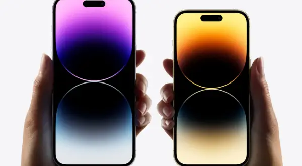 Dwie dłonie trzymają telefony iPhone 16. Jeden z nich ma fioletowy ekran, drugi złoty.