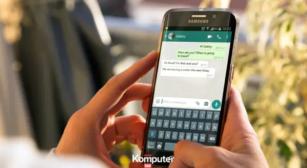 Dłoń trzyma smartfon z otwartym WhatsAppem, pokazując rozmowę. Dowiedz się, jak zainstalować WhatsApp.