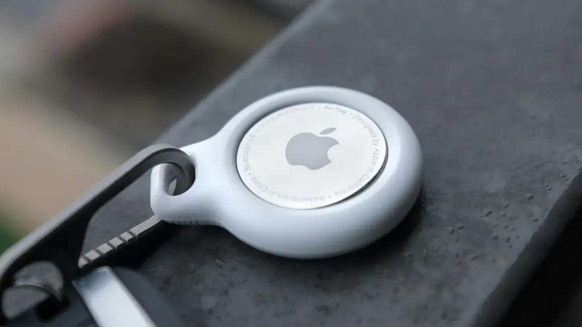 Biały AirTag od Apple, z logo i napisem "Designed by Apple in California". To urządzenie, które pomoże Ci odnaleźć zgubione przedmioty.