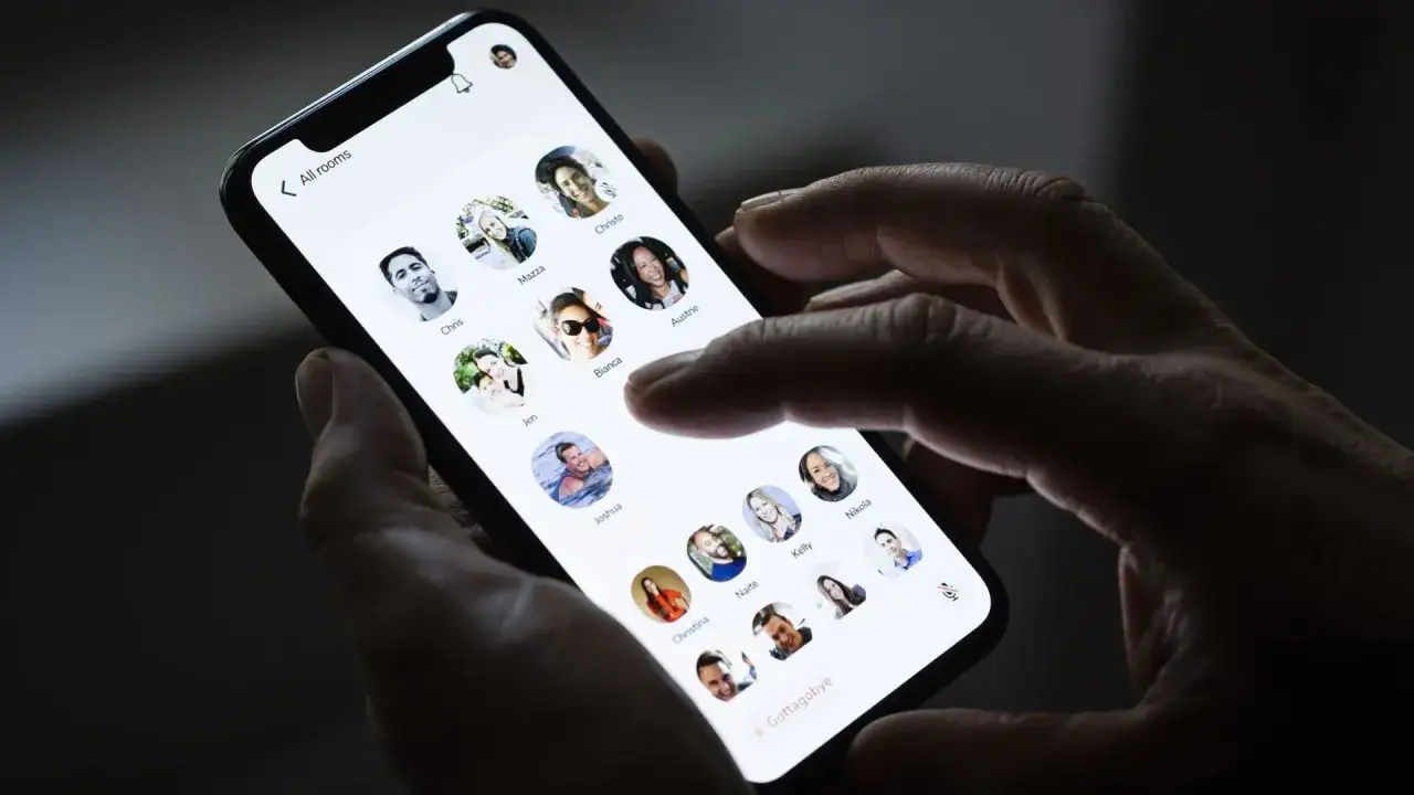 Dłoń trzyma smartfon z otwartą aplikacją clubhouse, wyświetlającą profile użytkowników.