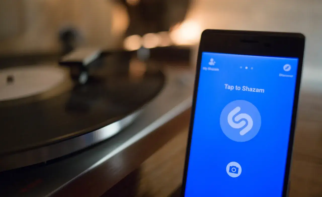 Telefon z aplikacją Shazam obok gramofonu. Chcesz wiedzieć, jaka to piosenka? Wystarczy dotknąć ekranu.