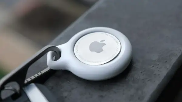 Biały AirTag od Apple, z logo i napisem "Designed by Apple in California". To urządzenie, które pomoże Ci odnaleźć zgubione przedmioty.