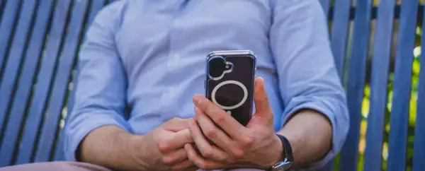 Mężczyzna w niebieskiej koszuli trzyma telefon z widocznym okręgiem, który sugeruje zaawansowaną haptykę.